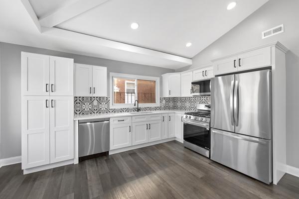 kitchen featuring dark hardwood / wood-style flooring, white cabinets, lofted ceiling, and appliances with stainless steel finishes