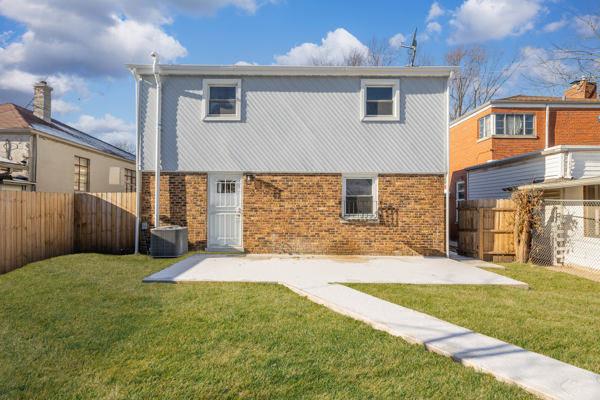 rear view of house featuring a yard, central AC unit, and a patio area