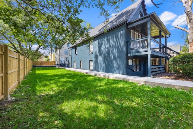 view of side of property with a balcony and a lawn