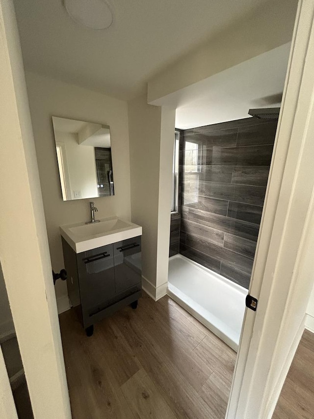 bathroom with hardwood / wood-style flooring, vanity, and tiled shower