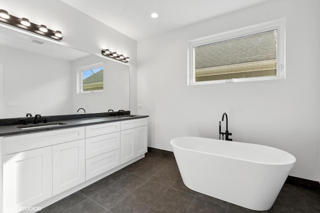 bathroom with a tub to relax in, tile patterned flooring, and vanity