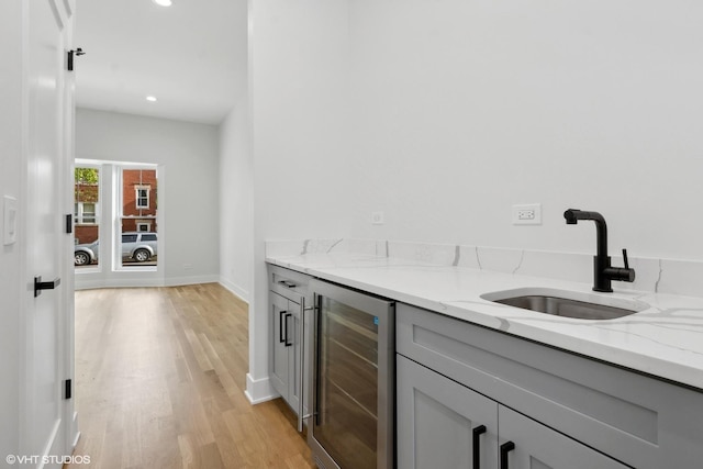 bar featuring sink, wine cooler, gray cabinetry, and light stone counters