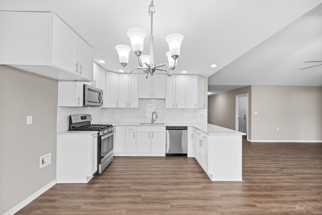 kitchen with white cabinets, decorative light fixtures, stainless steel appliances, and dark wood-type flooring