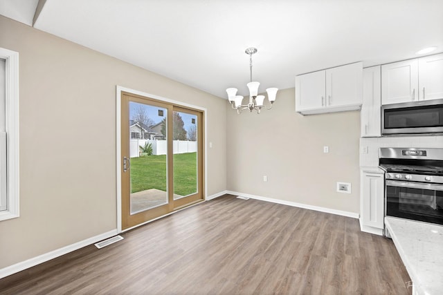 kitchen with stainless steel appliances, light hardwood / wood-style flooring, a notable chandelier, decorative light fixtures, and white cabinets