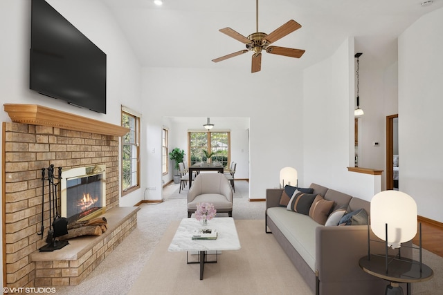 carpeted living room featuring ceiling fan, a fireplace, and high vaulted ceiling