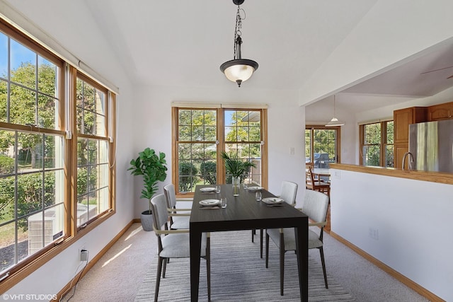 dining area featuring carpet floors, vaulted ceiling, a healthy amount of sunlight, and sink