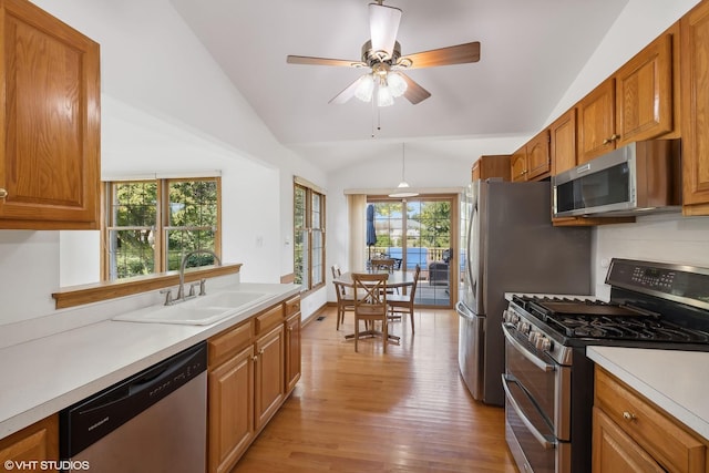 kitchen with appliances with stainless steel finishes, light hardwood / wood-style floors, lofted ceiling, and sink