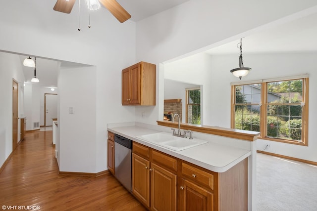 kitchen featuring kitchen peninsula, sink, dishwasher, light hardwood / wood-style floors, and hanging light fixtures