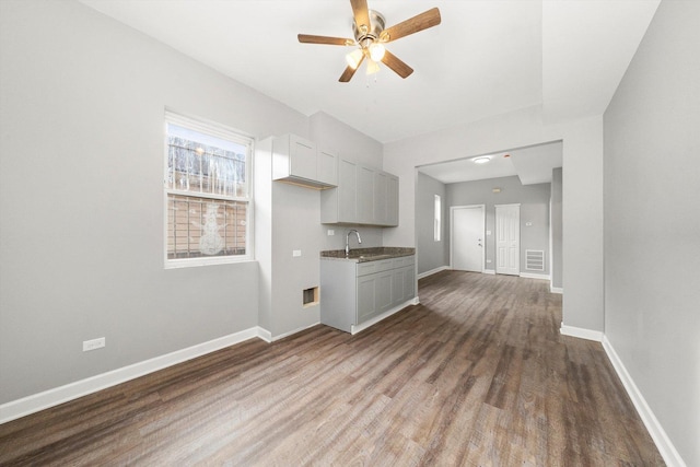 unfurnished living room with ceiling fan, sink, and hardwood / wood-style flooring