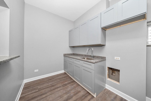 kitchen featuring dark hardwood / wood-style flooring, light stone counters, and sink