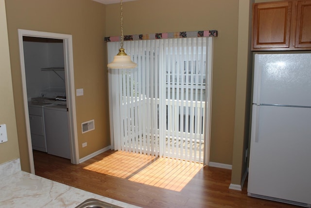 kitchen with pendant lighting, washing machine and dryer, white fridge, and dark hardwood / wood-style flooring