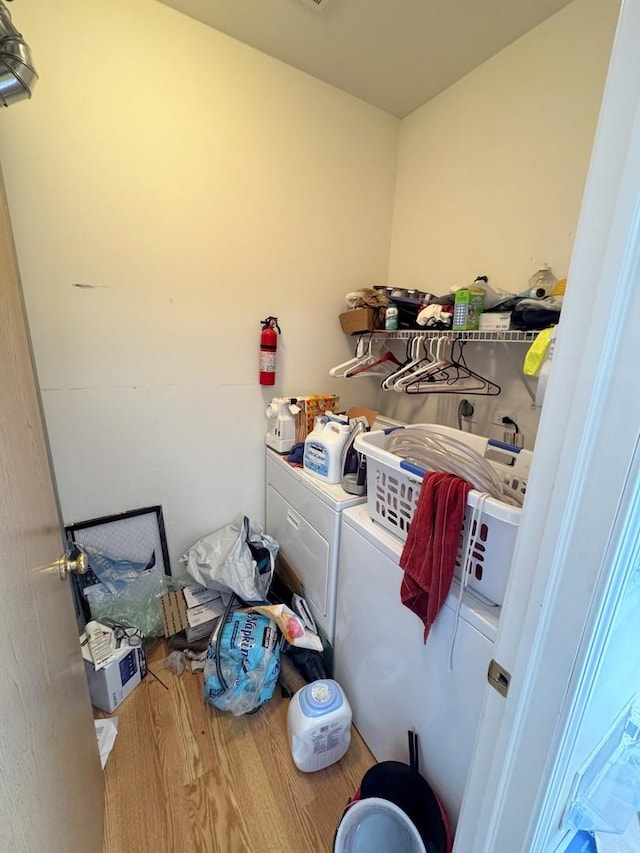 clothes washing area with washing machine and clothes dryer and wood-type flooring