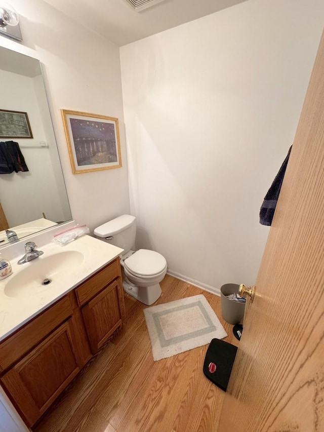 bathroom with wood-type flooring, vanity, and toilet