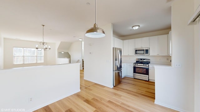 kitchen featuring hanging light fixtures, light hardwood / wood-style flooring, white cabinets, and stainless steel appliances