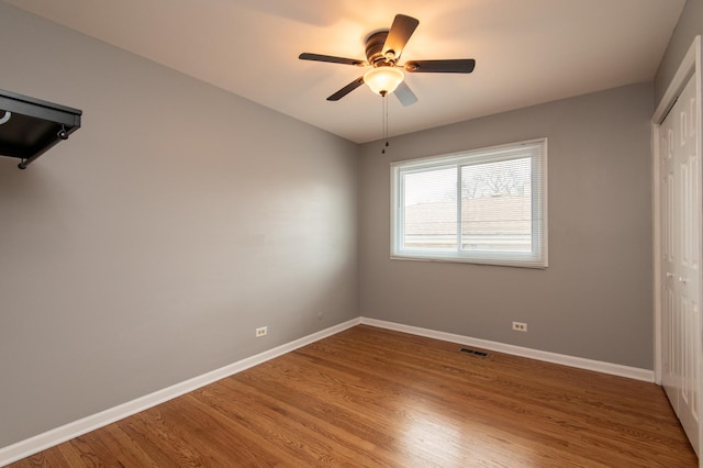 unfurnished bedroom featuring ceiling fan, a closet, and hardwood / wood-style flooring