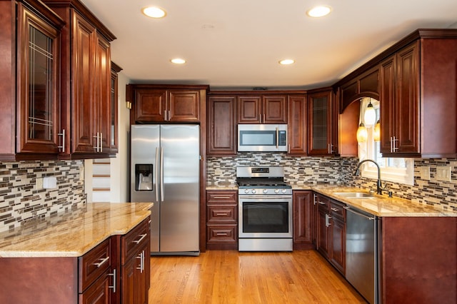 kitchen with sink, stainless steel appliances, tasteful backsplash, light stone counters, and light hardwood / wood-style floors