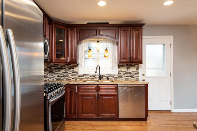 kitchen with backsplash, stainless steel appliances, light hardwood / wood-style floors, and sink