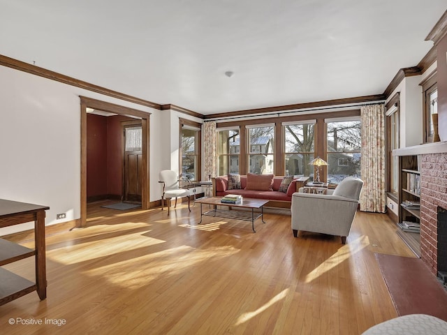 living room with light wood-type flooring, a brick fireplace, and crown molding