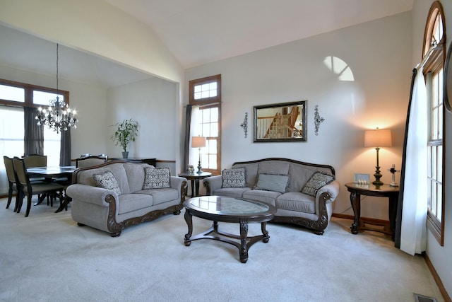 carpeted living room with a notable chandelier and lofted ceiling