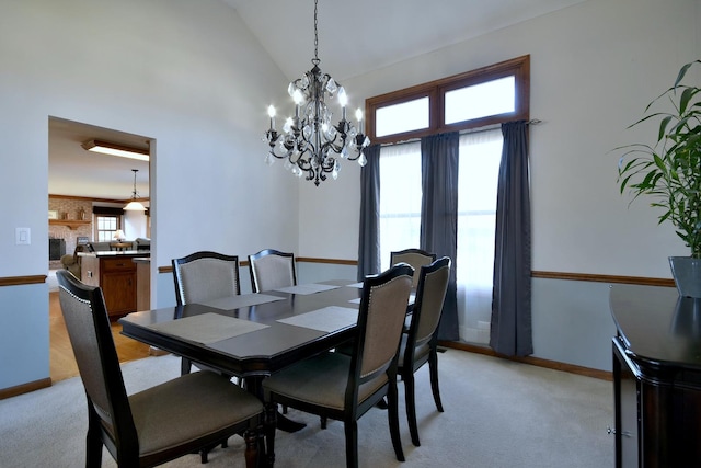 carpeted dining space featuring a large fireplace, vaulted ceiling, and a notable chandelier