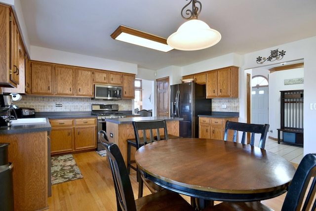 kitchen with sink, light hardwood / wood-style flooring, decorative backsplash, a kitchen island, and appliances with stainless steel finishes