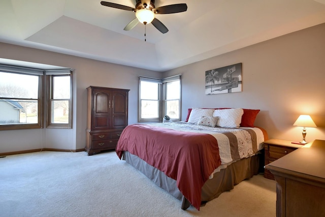 bedroom with a raised ceiling, ceiling fan, and light colored carpet