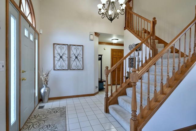 foyer with light tile patterned floors, a healthy amount of sunlight, a notable chandelier, and a high ceiling