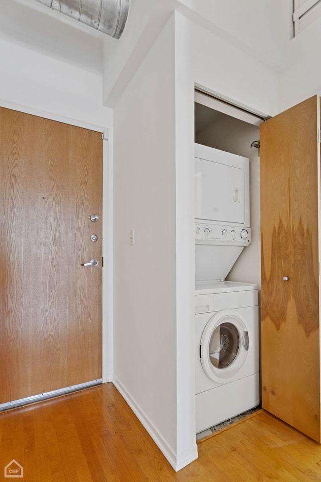 clothes washing area featuring stacked washer and dryer and hardwood / wood-style floors