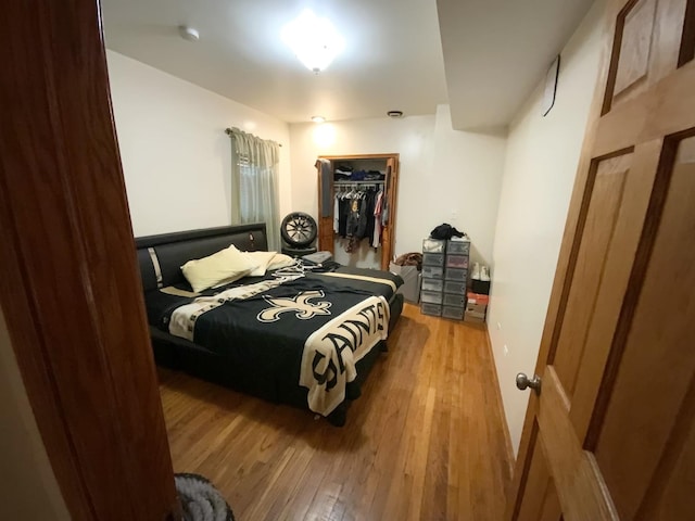 bedroom with a walk in closet, a closet, and hardwood / wood-style floors