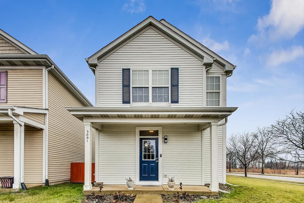 front facade featuring covered porch and a front lawn