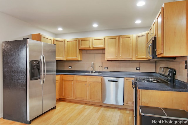 kitchen featuring light brown cabinets, sink, light wood-type flooring, tasteful backsplash, and stainless steel appliances