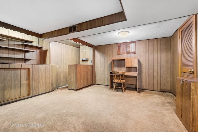 carpeted home office featuring a textured ceiling and wooden walls