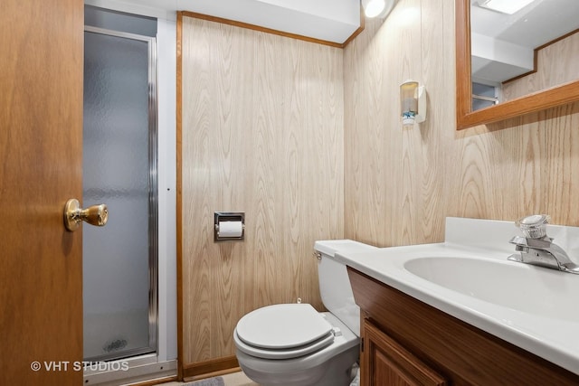 bathroom with vanity, wood walls, toilet, and a shower with door