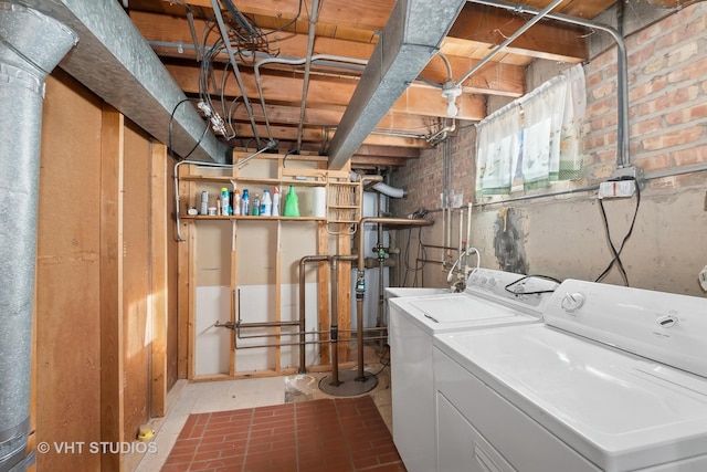 clothes washing area with separate washer and dryer and brick wall