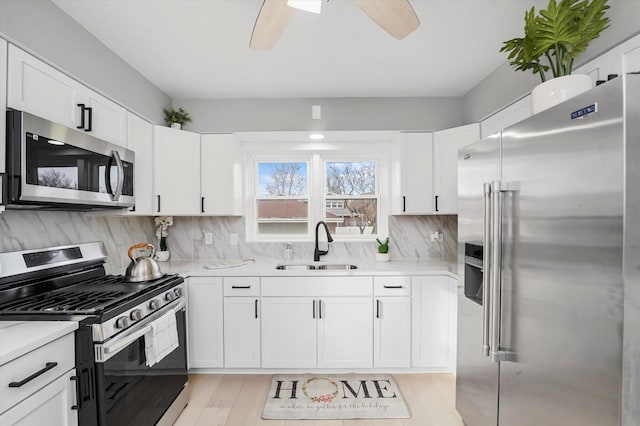 kitchen with white cabinets, light hardwood / wood-style floors, sink, and appliances with stainless steel finishes