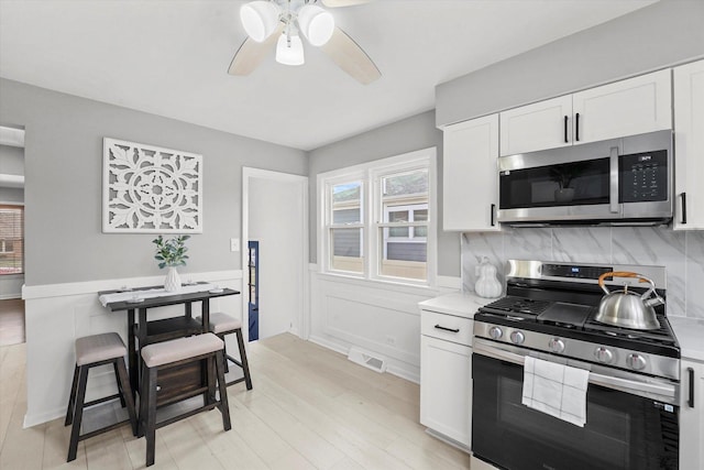 kitchen featuring white cabinets, appliances with stainless steel finishes, light hardwood / wood-style floors, and tasteful backsplash