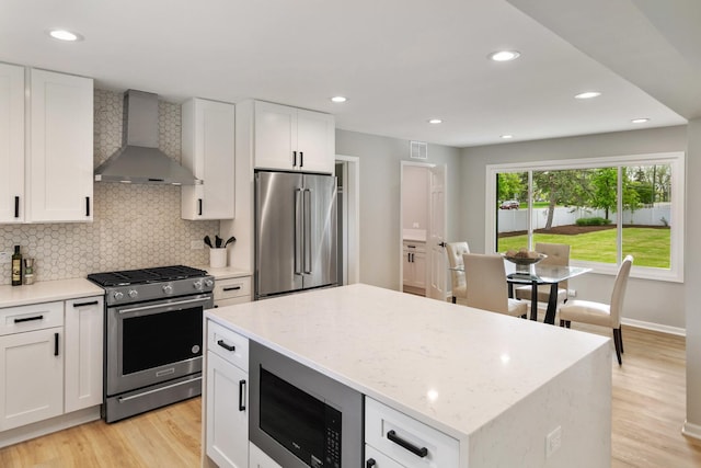 7S135 Clover Ct, Naperville, IL 60540 - kitchen featuring stainless steel appliances, wall chimney exhaust hood, light wood-style flooring, decorative backsplash, and a center island