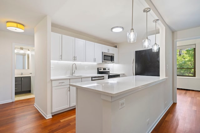 kitchen with white cabinetry, sink, light stone counters, dark hardwood / wood-style flooring, and appliances with stainless steel finishes