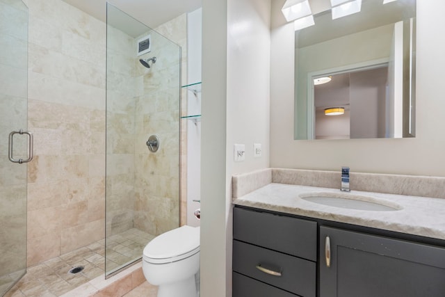 bathroom featuring tile patterned floors, vanity, toilet, and a shower with shower door