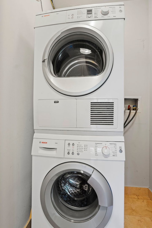 washroom with light tile patterned floors and stacked washer and dryer