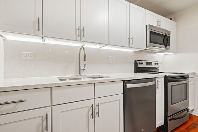 kitchen with dark wood-type flooring, white cabinets, sink, light stone countertops, and appliances with stainless steel finishes