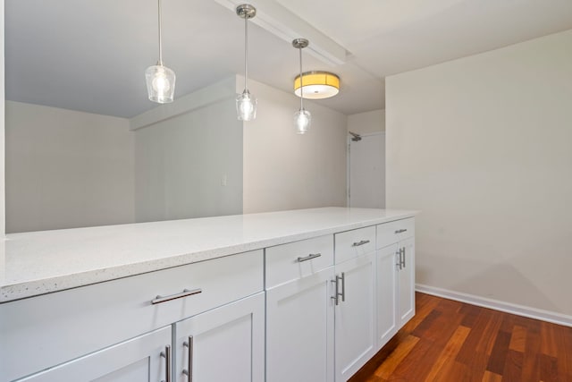 kitchen featuring light stone counters, white cabinets, hanging light fixtures, and dark hardwood / wood-style floors