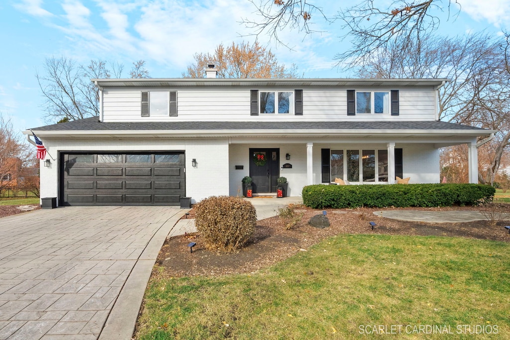 front of property featuring a front yard, a porch, and a garage