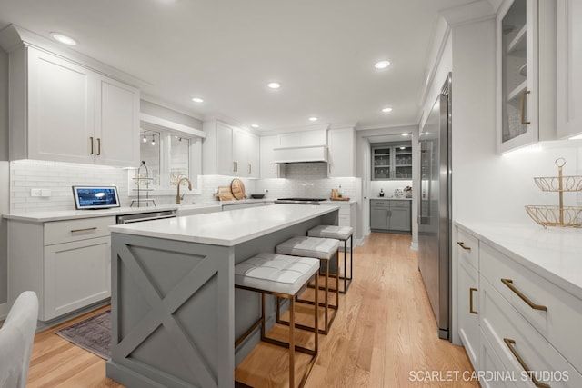 kitchen featuring white cabinetry, a breakfast bar, custom range hood, and light wood-type flooring