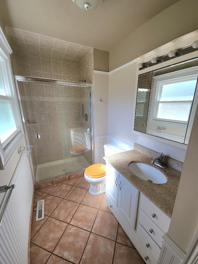 bathroom featuring tile patterned flooring, vanity, toilet, and an enclosed shower