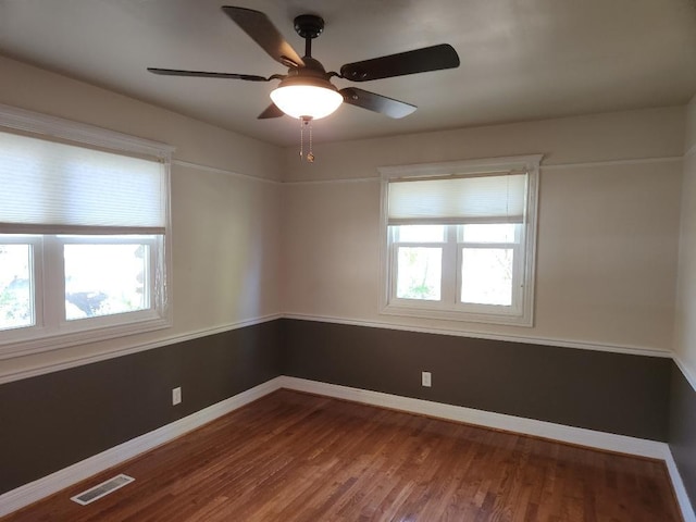 empty room featuring a wealth of natural light, ceiling fan, and hardwood / wood-style flooring