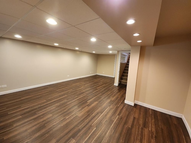 basement featuring a paneled ceiling and dark hardwood / wood-style flooring