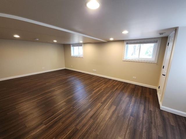 basement featuring a wealth of natural light and dark wood-type flooring