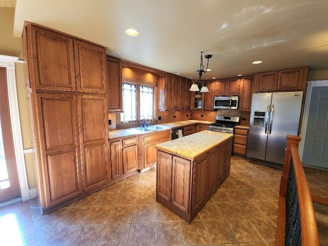 kitchen featuring a center island, dark tile patterned flooring, sink, decorative light fixtures, and stainless steel appliances