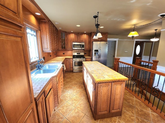 kitchen with a center island, sink, stainless steel appliances, and hanging light fixtures